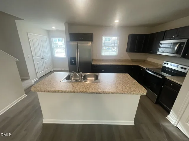 a bathroom with a granite countertop sink a toilet a mirror and window