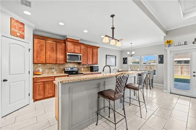 a kitchen with stainless steel appliances granite countertop a refrigerator a stove a sink and a dining table with chairs