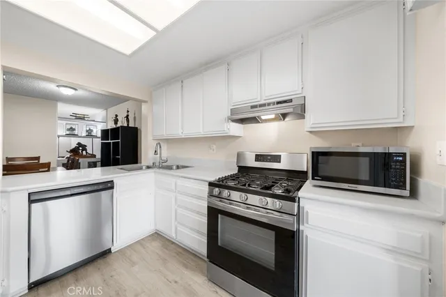 a kitchen with cabinets stainless steel appliances and a wooden floor