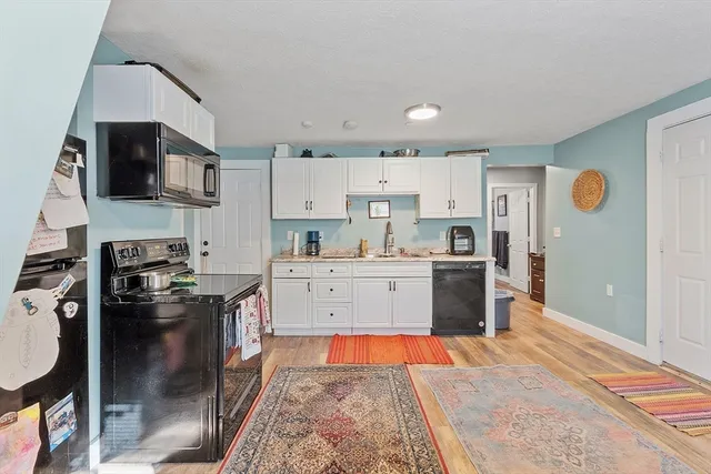 a kitchen with stainless steel appliances granite countertop a stove top oven a sink and white cabinets