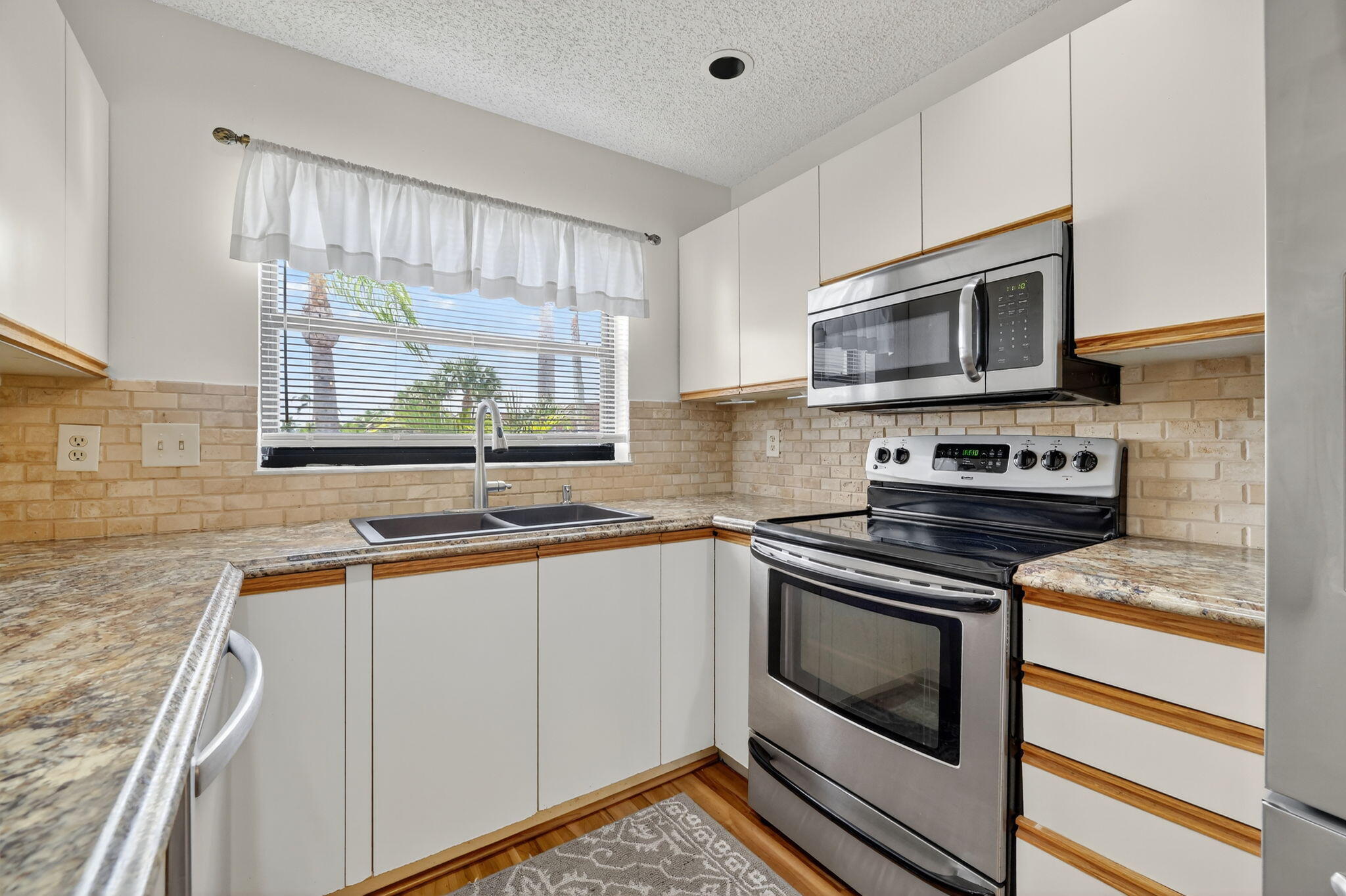 6101 Southeast Landing Way, Unit 11 Stuart, FL 34997 - Photo 12 of 55 a kitchen with stainless steel appliances a stove sink microwave and cabinets