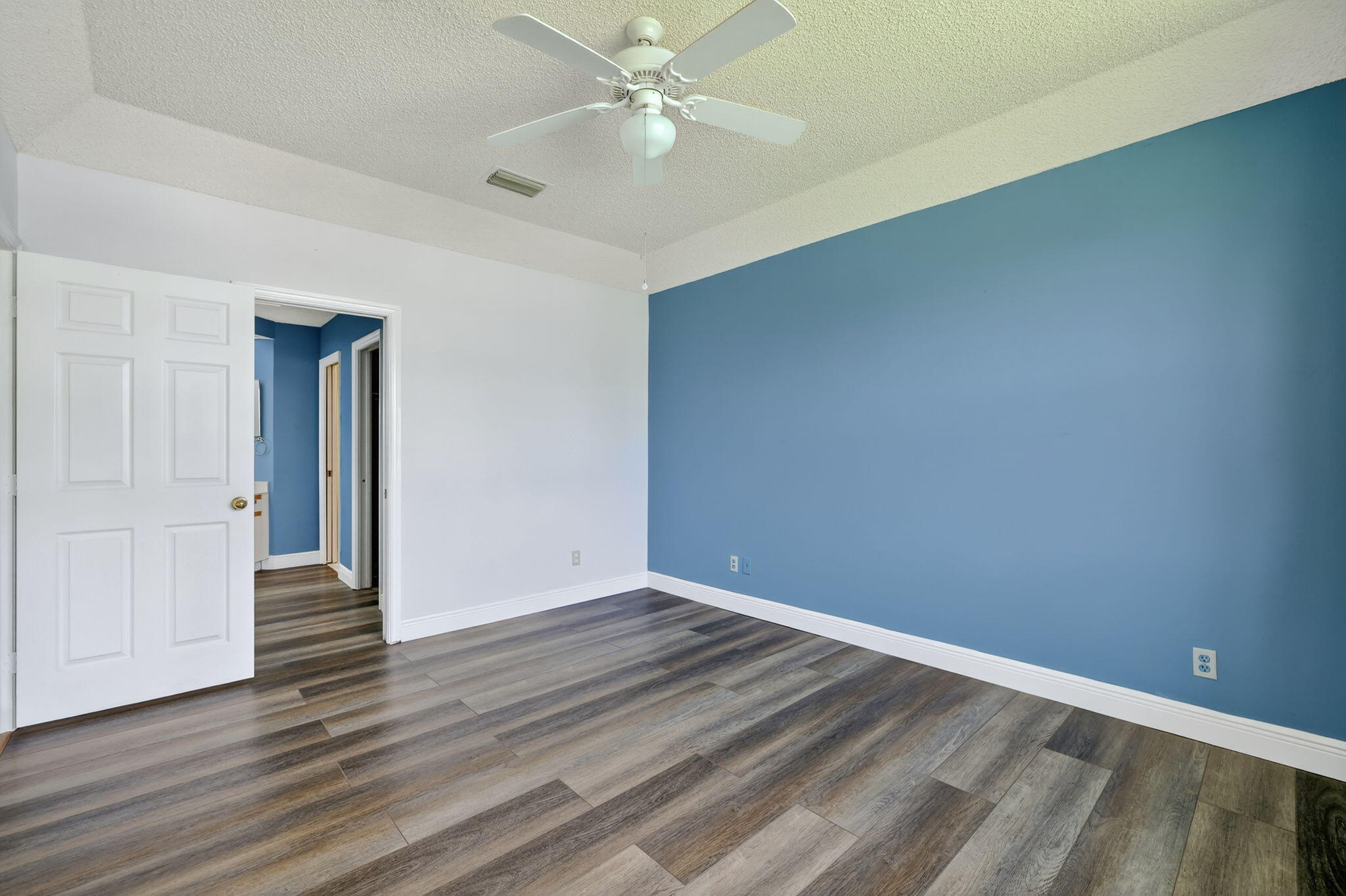 6101 Southeast Landing Way, Unit 11 Stuart, FL 34997 - Photo 17 of 55 a view of an empty room with wooden floor and a ceiling fan