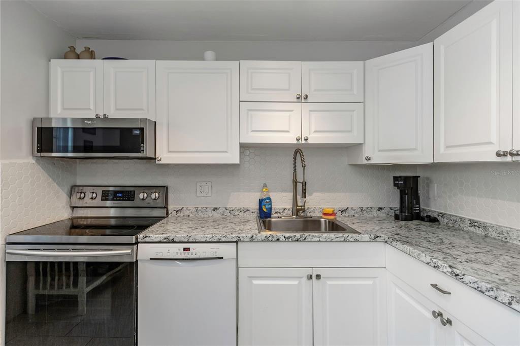 1900 68th Street North, Unit 110 St. Petersburg, FL 33710 - Photo 15 of 48 a kitchen with stainless steel appliances granite countertop a stove a sink a microwave and cabinets