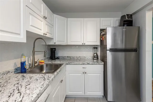 a kitchen with stainless steel appliances granite countertop a refrigerator sink and white cabinets