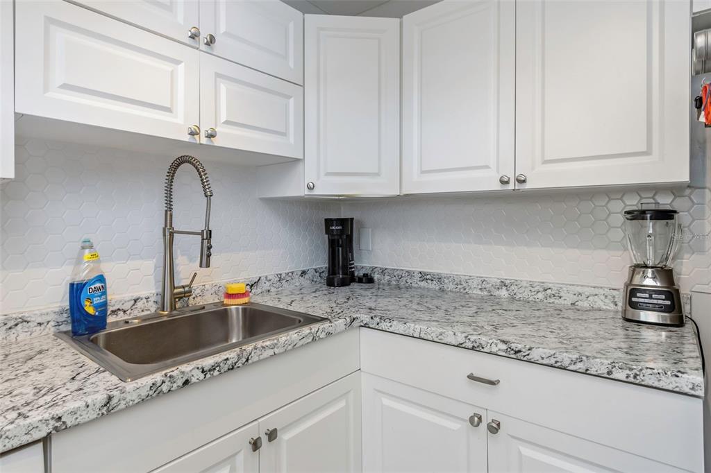 1900 68th Street North, Unit 110 St. Petersburg, FL 33710 - Photo 17 of 48 a kitchen with granite countertop a sink stainless steel appliances white cabinets and a granite counter tops