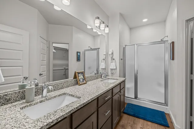 a bathroom with a granite countertop sink a mirror and shower