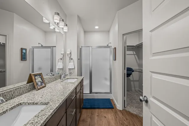 a bathroom with a granite countertop sink a mirror and shower