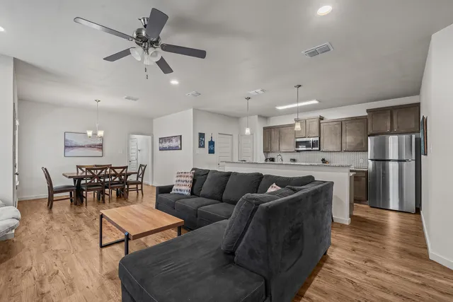 a living room with stainless steel appliances furniture and a kitchen view