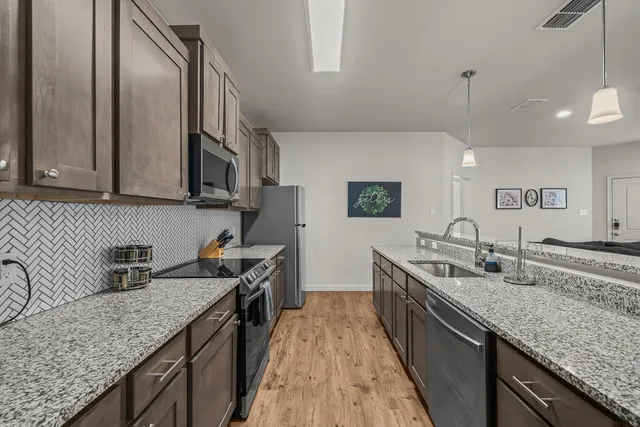a kitchen with granite countertop stainless steel appliances a sink stove and cabinets