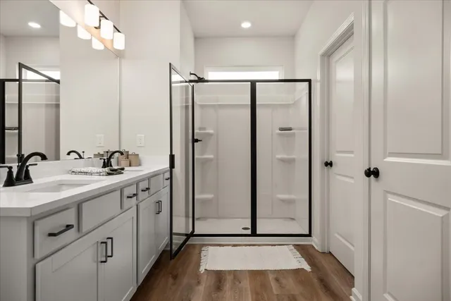 a bathroom with a double vanity sink a mirror a shower and a glass door