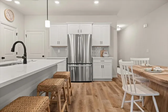 a kitchen with stainless steel appliances a refrigerator a sink a stove and white cabinets with wooden floor