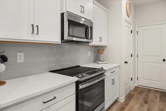a kitchen with stainless steel appliances white cabinets and a stove top oven