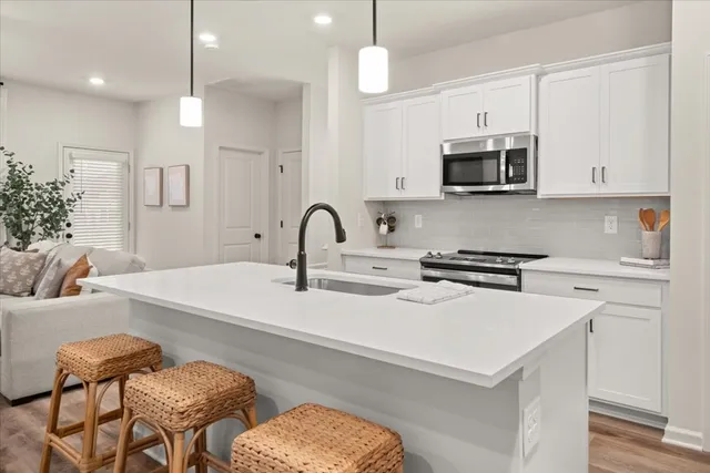 a kitchen with stainless steel appliances a stove a sink and white cabinets