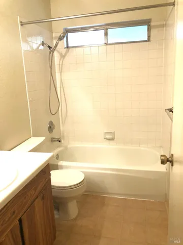 a bathroom with a granite countertop shower sink vanity mirror and toilet