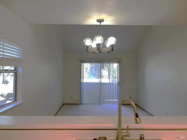 a view of a hallway with windows and chandelier