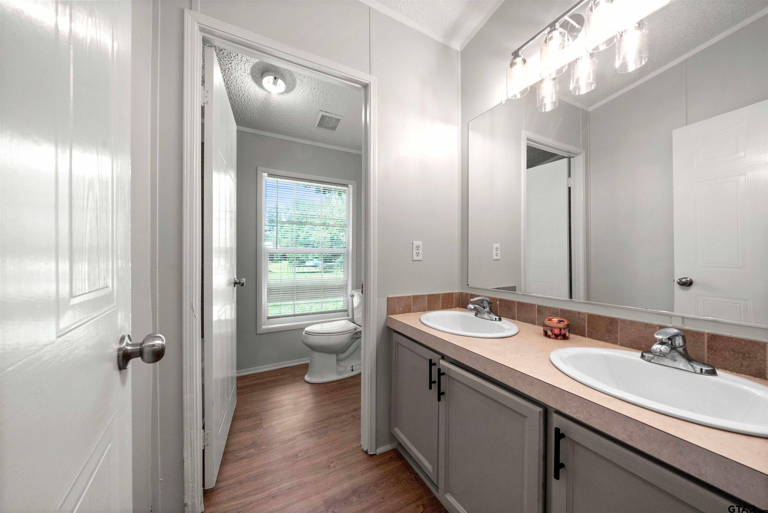 10490 Peterson Tyler, TX 75708 - Photo 15 of 30 a bathroom with a granite countertop sink a large mirror a toilet and a shower