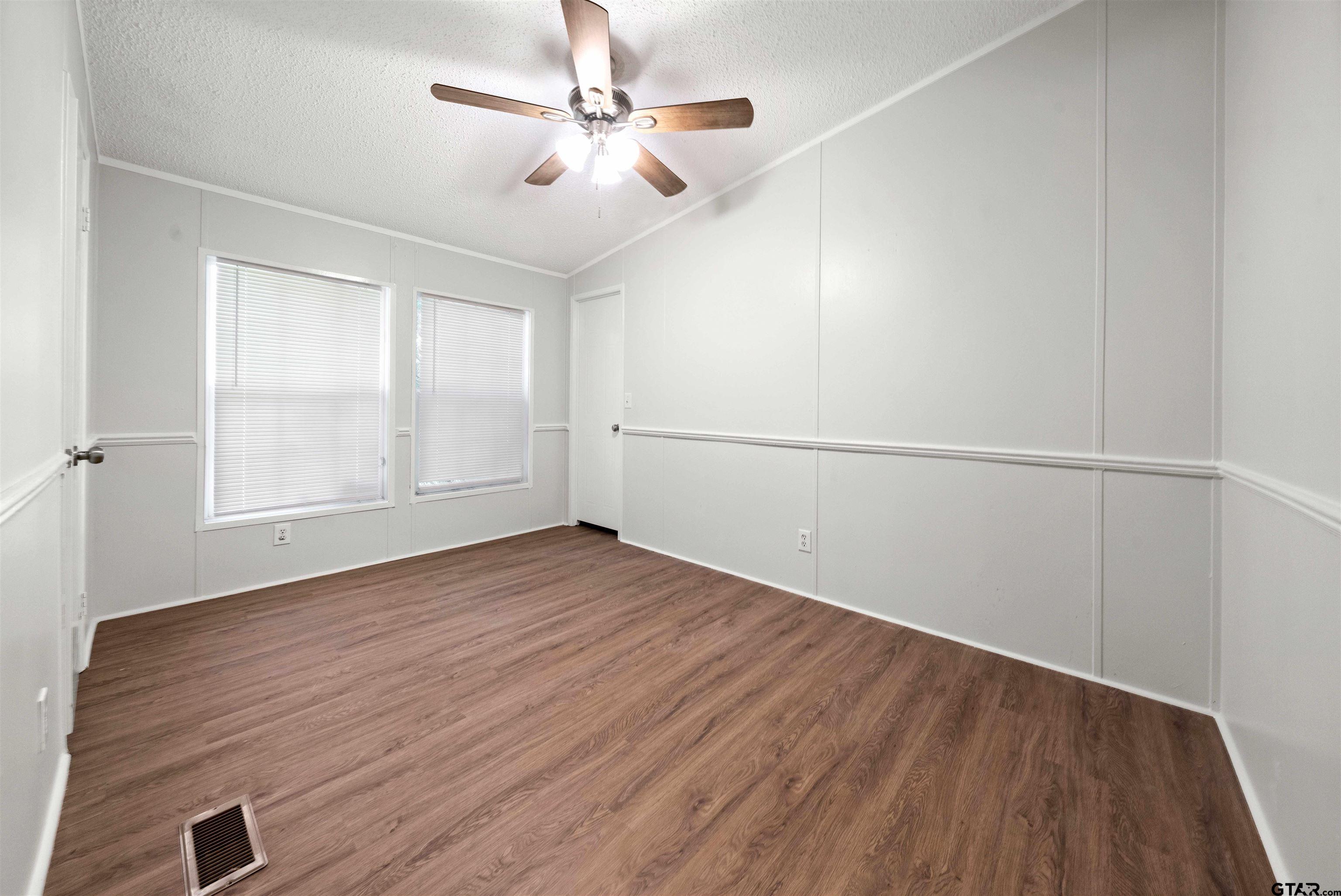 10490 Peterson Tyler, TX 75708 - Photo 22 of 30 an empty room with wooden floor chandelier fan and windows