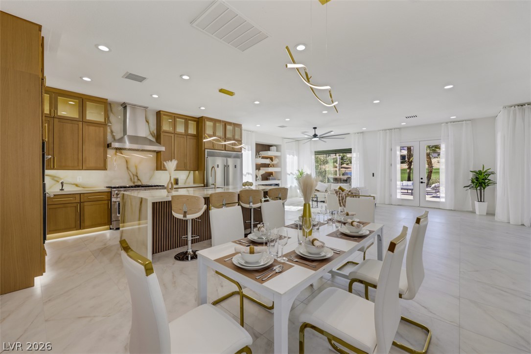 5015 Rivedro Street Las Vegas, NV 89135 - Photo 30 of 91 An open-concept living space integrates a stylish dining area with a gourmet kitchen, all illuminated by recessed lighting.