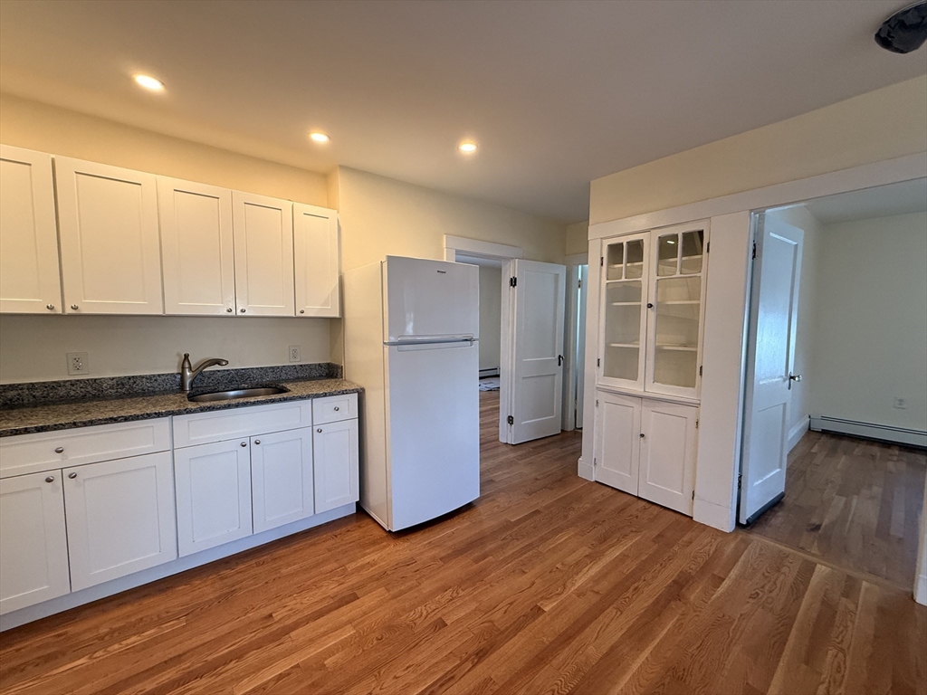 a kitchen with granite countertop white cabinets and refrigerator