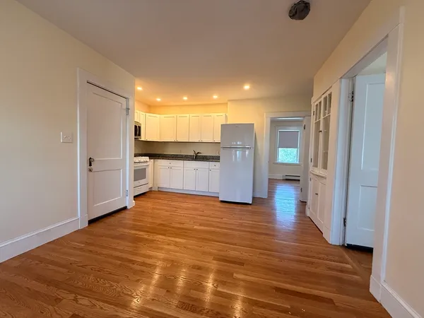 a view of a kitchen with wooden floor and a refrigerator