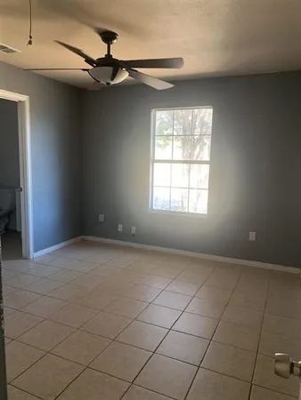 an empty room with windows and fan