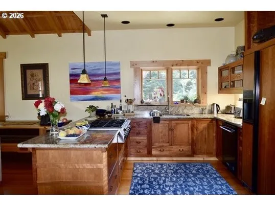 a kitchen with granite countertop a stove a sink a refrigerator and a dining table