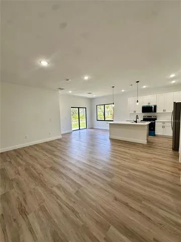 a view of an empty room with kitchen view and a counter top space