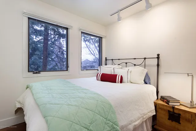 a bedroom with a bed and two window