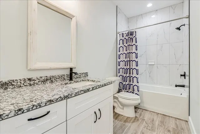a bathroom with a granite countertop sink a toilet and shower