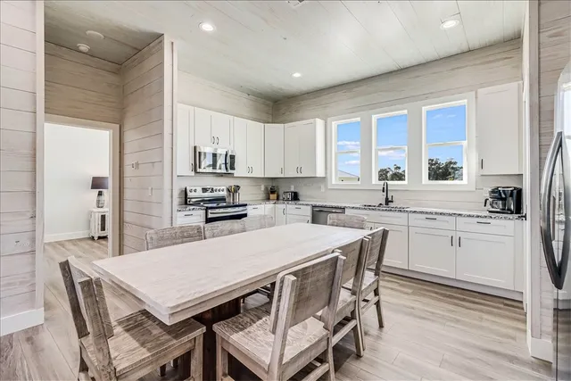 a kitchen with a table a sink cabinets and stainless steel appliances