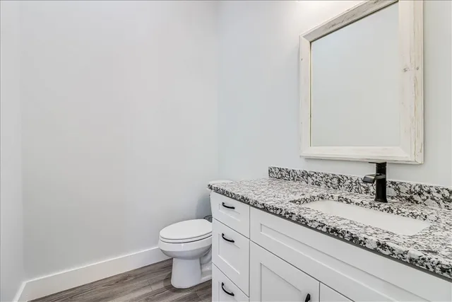 a bathroom with a granite countertop toilet sink and mirror