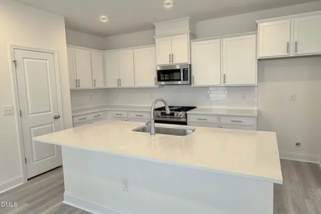 a kitchen with stainless steel appliances a white stove top oven a sink a refrigerator and white cabinets