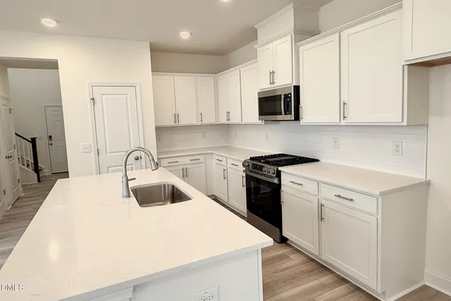 a kitchen with granite countertop a sink stove and white cabinets