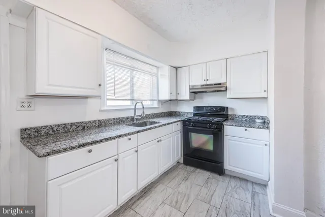 a kitchen with granite countertop a sink stove and cabinets