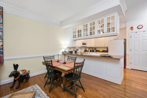 a dining room with stainless steel appliances a wooden floor a dining table and chairs