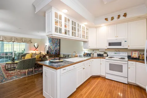 a kitchen with a stove a sink and white cabinets with wooden floor