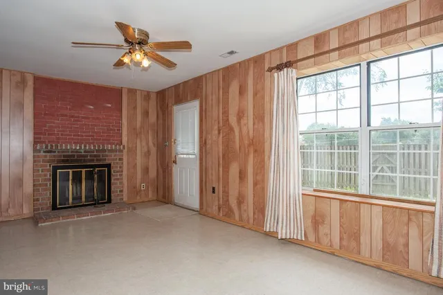 a view of an empty room with chandelier fan and fire place