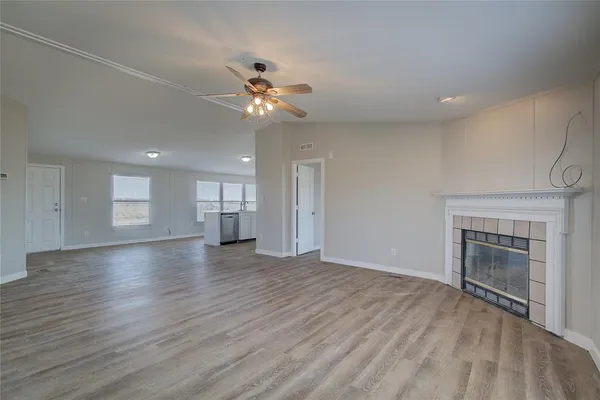 an empty room with wooden floor fireplace and windows