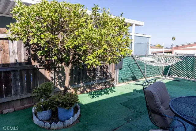 a view of a backyard with table and chairs potted plants and tree