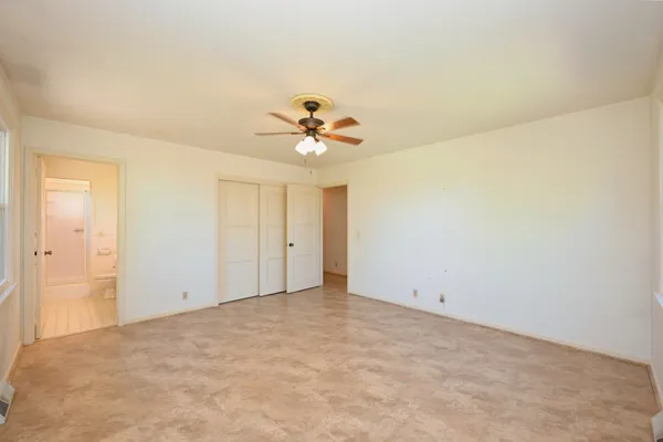 an empty room with windows and chandelier fan