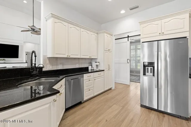 a kitchen with granite countertop a refrigerator stove and sink