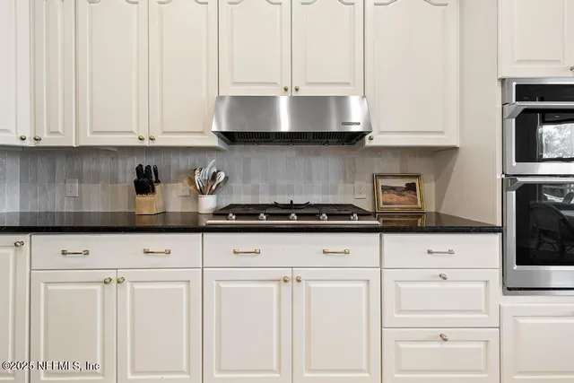 a kitchen with stainless steel appliances granite countertop white cabinets and a stove