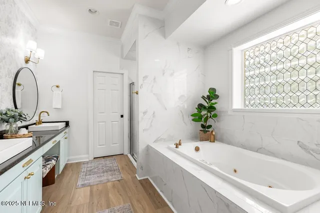 a bathroom with a bathtub a sink a window and a potted plant