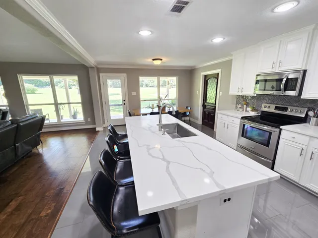 a kitchen with kitchen island a stove a sink a refrigerator and cabinets