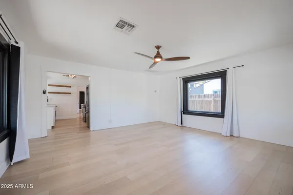 a view of an empty room with a window and a kitchen
