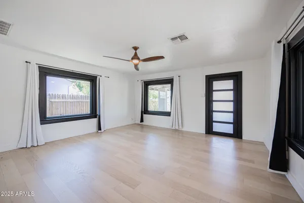 a view of an empty room with window and wooden floor