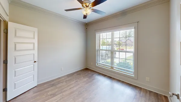 an empty room with wooden floor fan and windows