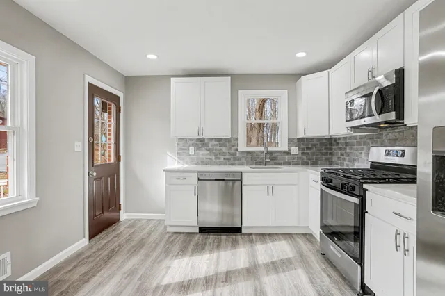 a kitchen with stainless steel appliances granite countertop a stove top oven a sink and dishwasher a refrigerator with wooden floor