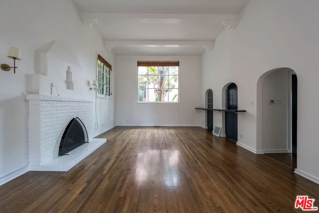 a view of empty room with wooden floor fireplace and window