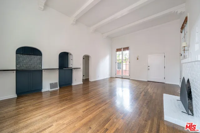 a view of empty room with wooden floor and tv
